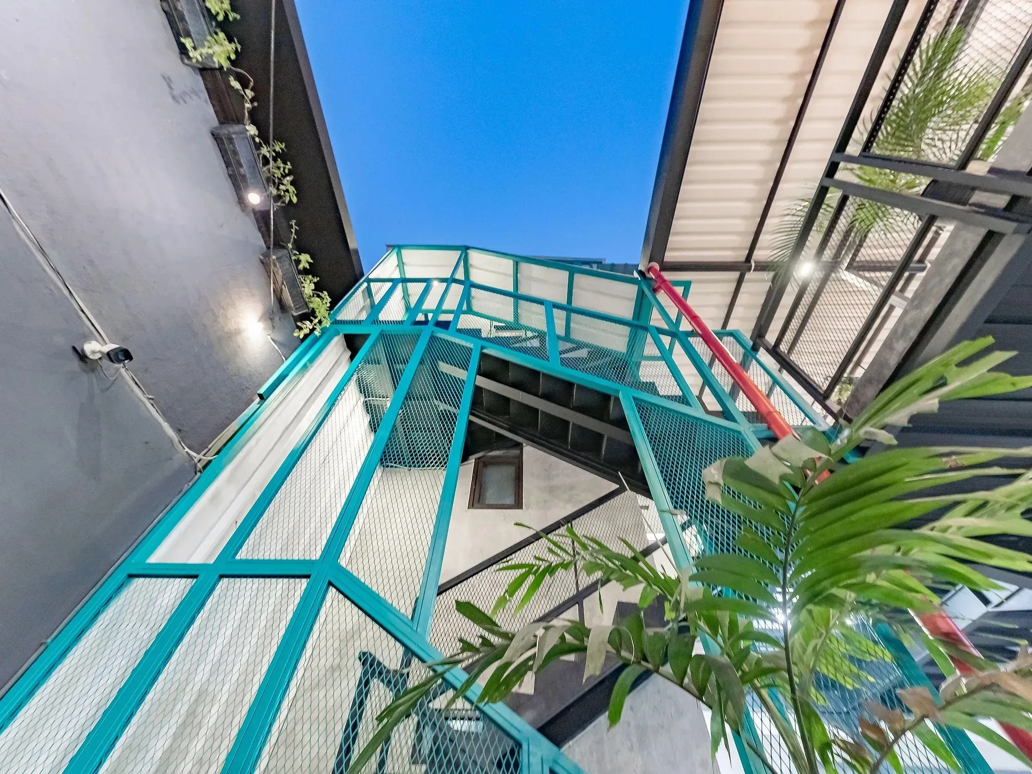 Atrium skylight with teal steel beams and hanging plants